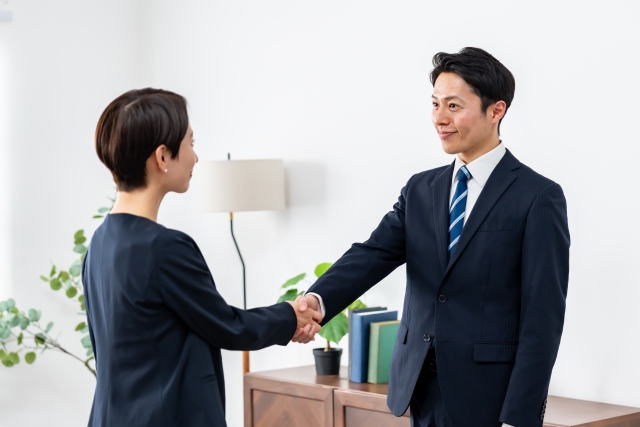 握手を交わすスーツ姿の男女のビジネスシーン