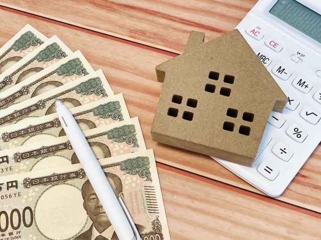 住宅資金をイメージした家模型と紙幣と電卓
