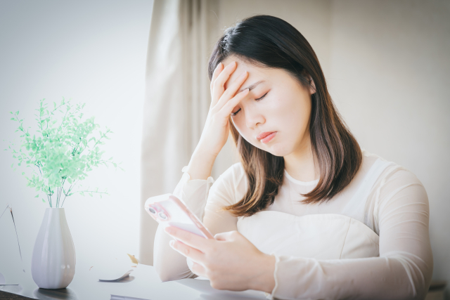 スマホの画面を見て悩む女性