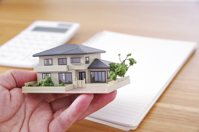 手のひらに乗せた住宅模型と資金計画
