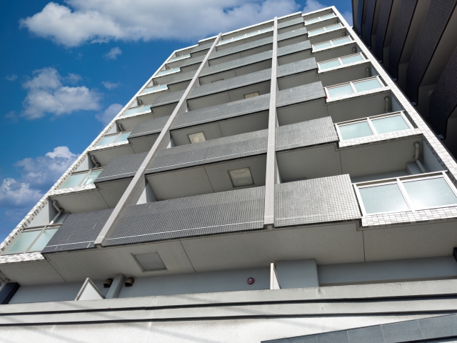青空にそびえる白い高層マンション