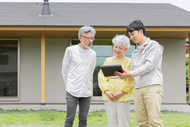 住宅前で説明を受けるシニア夫婦